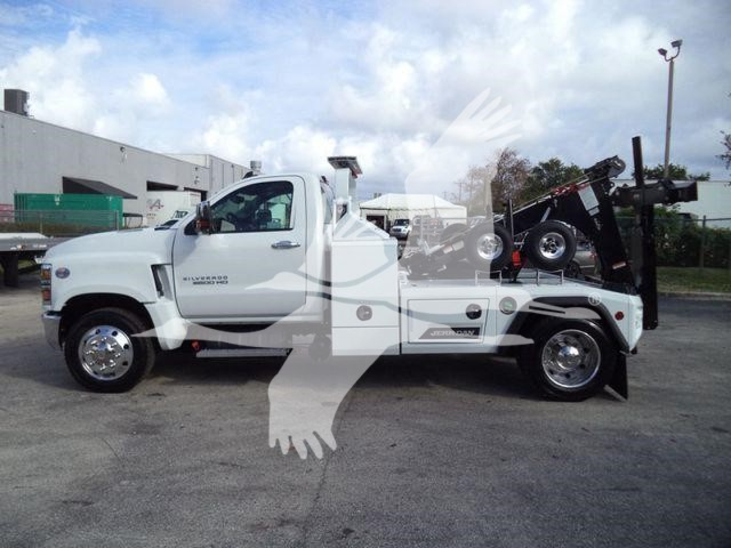 White Chevrolet Silverado 6500HD tow truck chassis in a lot with winch equipment on the bed and towing crane visible.