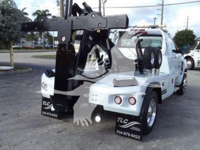 Tow truck with heavy-duty winch and boom assembly mounted on flatbed chassis, front view showing winch arm and hooks.