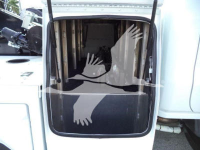 Truck cargo area interior showing winch equipment and open rear door with hydraulic lines visible.