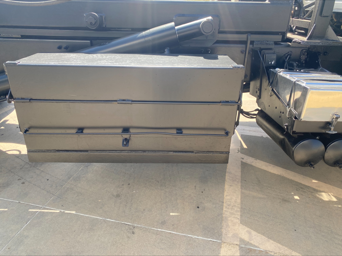 Mack GU533 truck side showing a large metal storage box and hydraulic components with a metal toolbox attached.