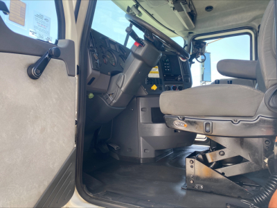 Truck cabin interior of a 2018 Mack GU533 with driver seat, steering wheel, dashboard, and entry door visible.