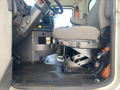 Truck cab interior showing driver seat and dashboard of a 2018 Mack GU533 roll-off truck.
