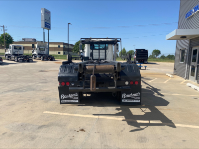 Rear view of a 2018 Mack GU533 roll-off truck showing towing hitch, bumper, taillights, and mudflaps with Buckner's logo. Stock plates and dealership signage visible.