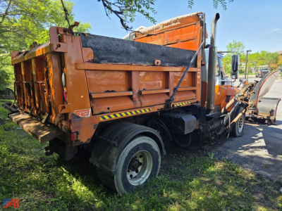 Dump truck body showing plow and sander equipment on International WorkStar 7400, orange cargo bed, hydraulic components visible.