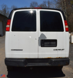 Rear view of a white 2004 Chevrolet Express 3500 cargo van with two back doors, black rear bumper, and a small rust line along the lower edge. Chevrolet badge on right door and blank license plate area.