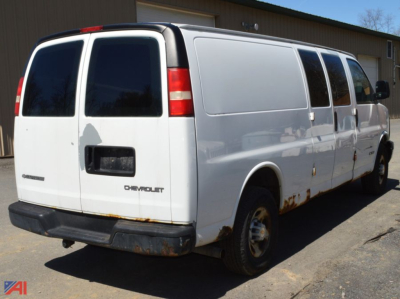 Chevrolet Express 3500 cargo van rear view showing white body, black bumper, and passenger-side sliding door.