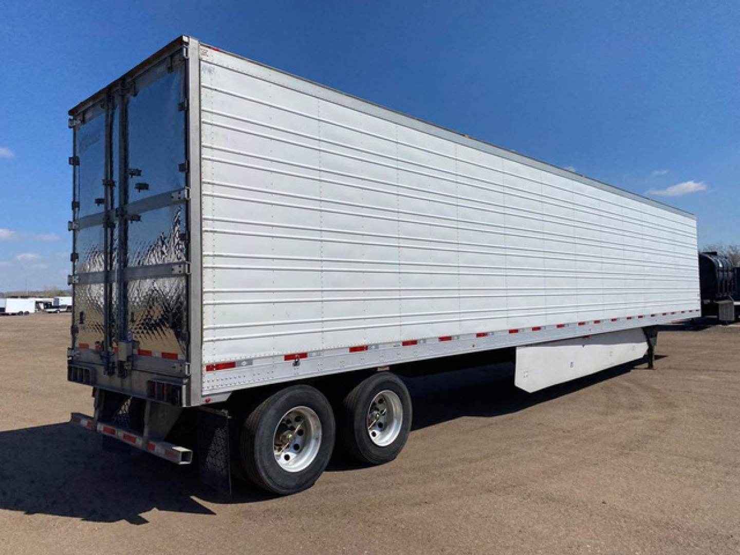 Trailer showing a white refrigerated box with dual rear doors and tandem axles.