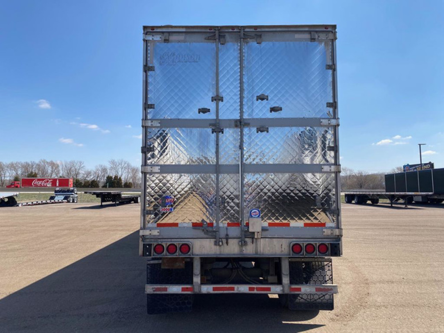 Trailer rear view of a 2018 Utility Reefer with diamond plate aluminum doors, dual rear doors, taillights, and reflective tape. VIN 1UYVS253XJ2007317 visible in listing.