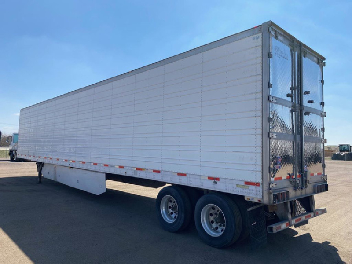 Utility reefer trailer in side view with tandem axles and rear doors. No legible branding visible; text not readable on image.