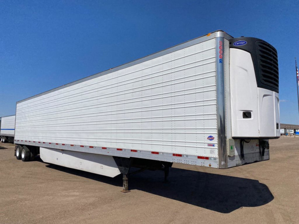 Trailer refrigeration unit with a white box and Carrier reefer at the front showing ThermoKing-style cooling unit, long silver sides, mounted on a painted chassis.