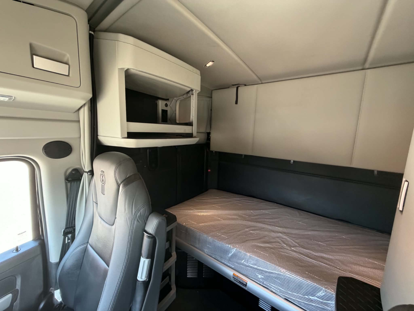 Kenworth T680 sleeper cab interior showing bunk bed and overhead storage compartment.