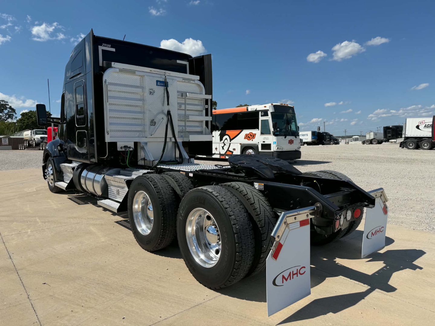 Kenworth T680 tractor with dual rear axles, fifth-wheel hitch, and sleeper cab; chrome fuel tanks and mud flaps visible; rear view showing back of cab and chassis.