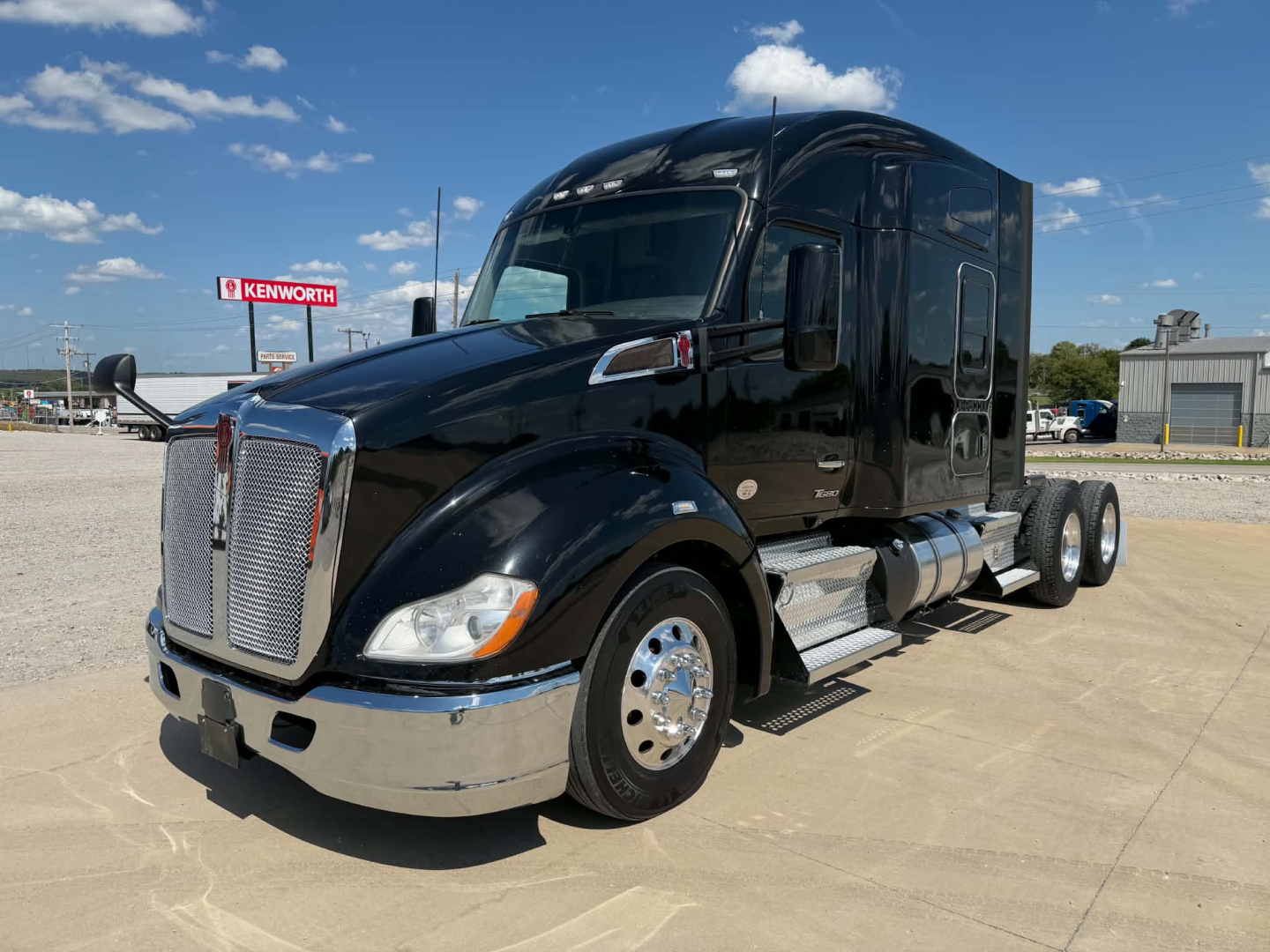 Kenworth T680 long-nose semi truck in black, front-left view showing chrome grille, headlights, and side fuel tanks.