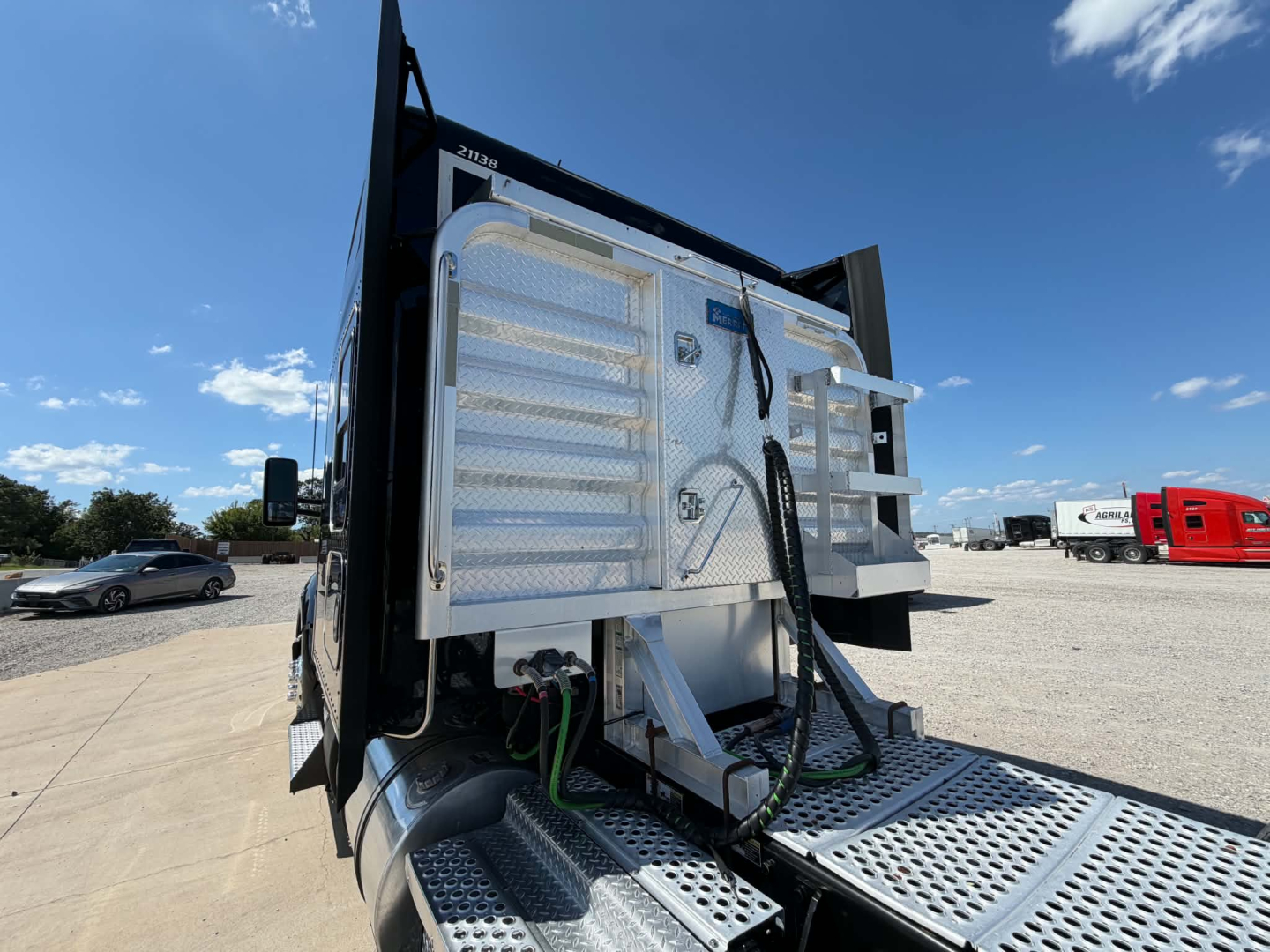 Kenworth T680 truck rear view showing tail area with chrome fuel lines and silver diamond plate steps.