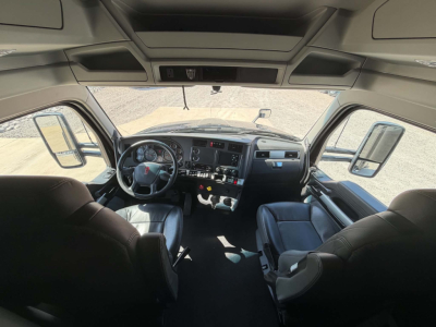 Kenworth T680 truck cab interior showing steering wheel, dashboard, and two captain seats; large windshield and side mirrors visible.