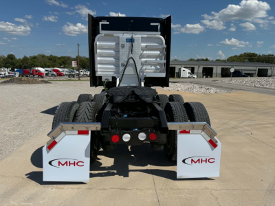 Kenworth T680 rear view showing fifth wheel, dual rear axles, and white MHC mudflaps with red logos.