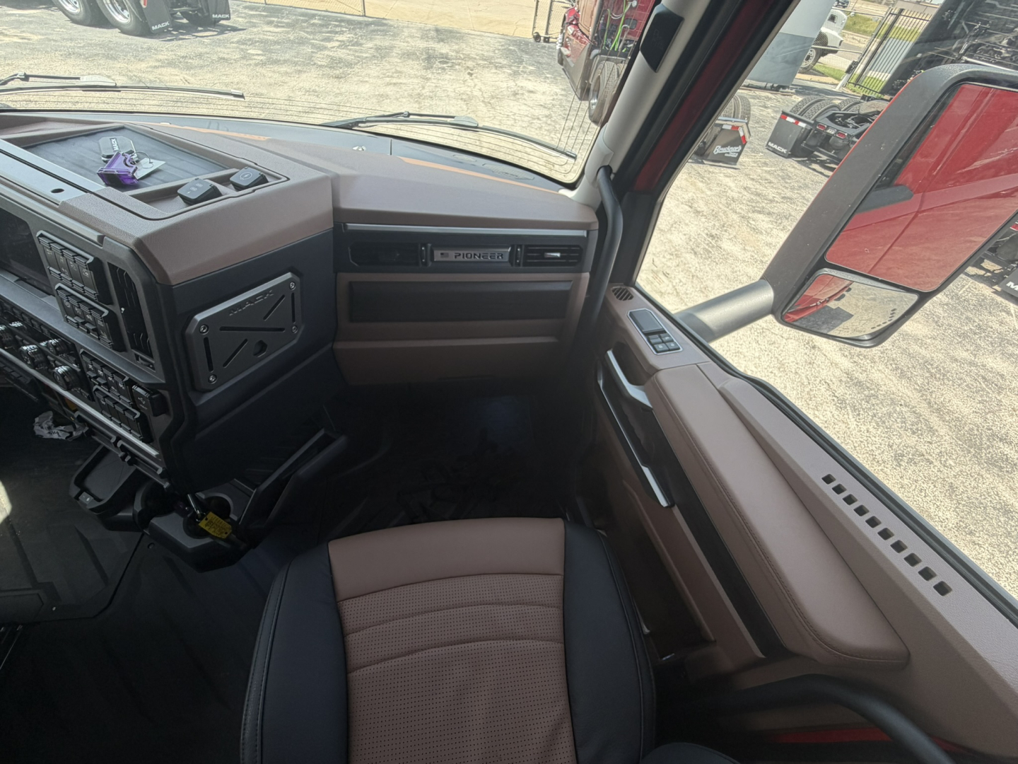 Mack truck cab interior showing dashboard controls and passenger seat area.