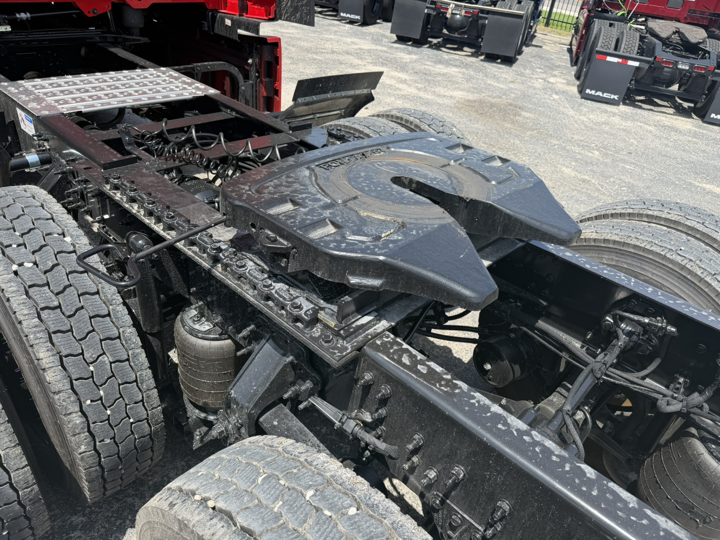 Chassis and fifth-wheel area of a new Mack PR64T76H truck showing drive axles, suspension, and fifth-wheel mounting.