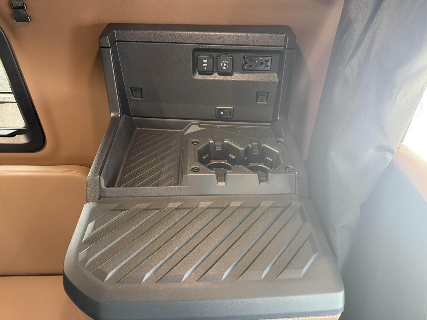 Truck interior cab storage area with power outlet and USB ports above a ribbed step surface.