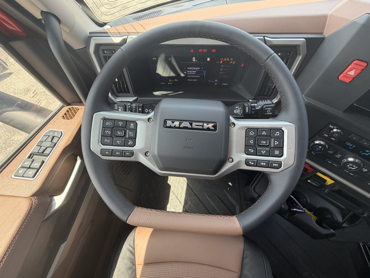 Mack PR64T76H steering wheel and dashboard with numerous control buttons visible in a truck cab interior.