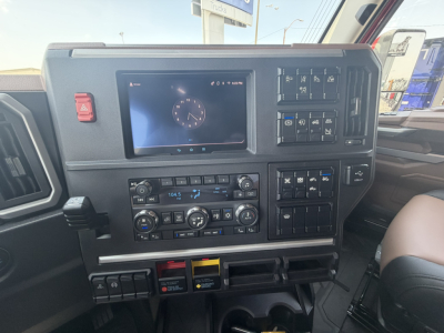 Dashboard interior of a 2027 Mack PR64T76H showing a digital instrument cluster, climate controls, media display, and multiple switches.