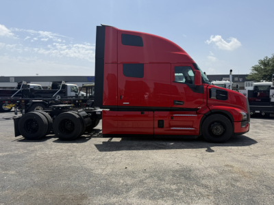 Truck side profile showing a red 2027 Mack PR64T76H conventional sleeper tractor chassis with dual rear axles and black wheels.