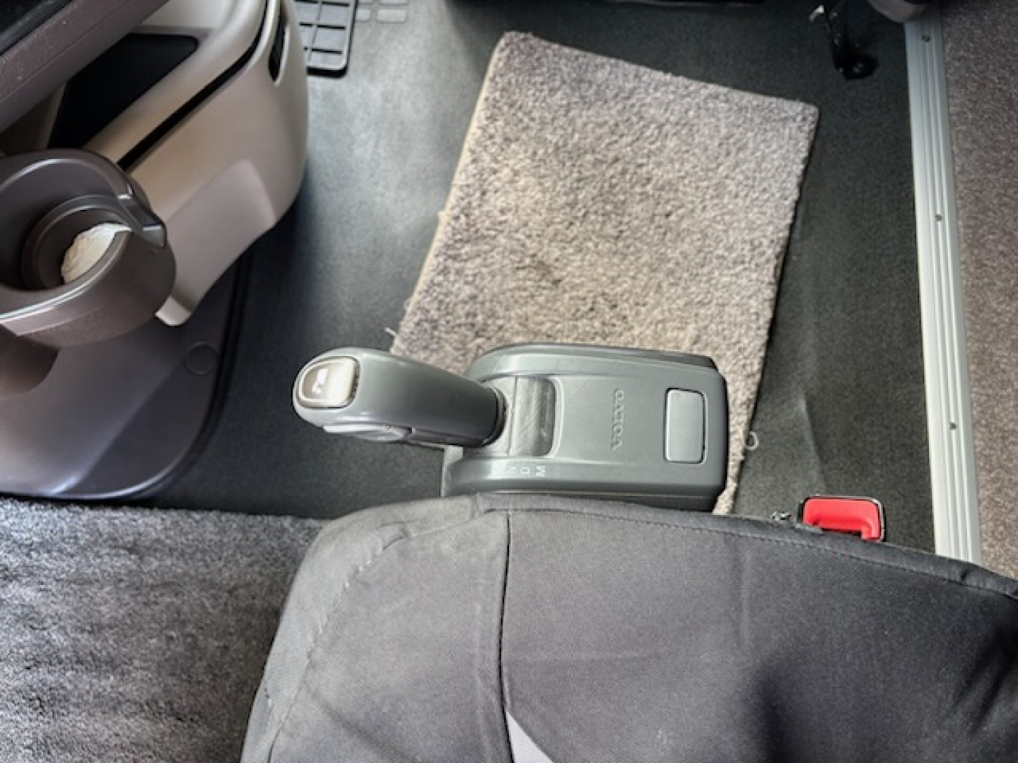 Cab interior of a 2016 Volvo VNL780 showing center console with gear shifter, cup holder, and floor mat.