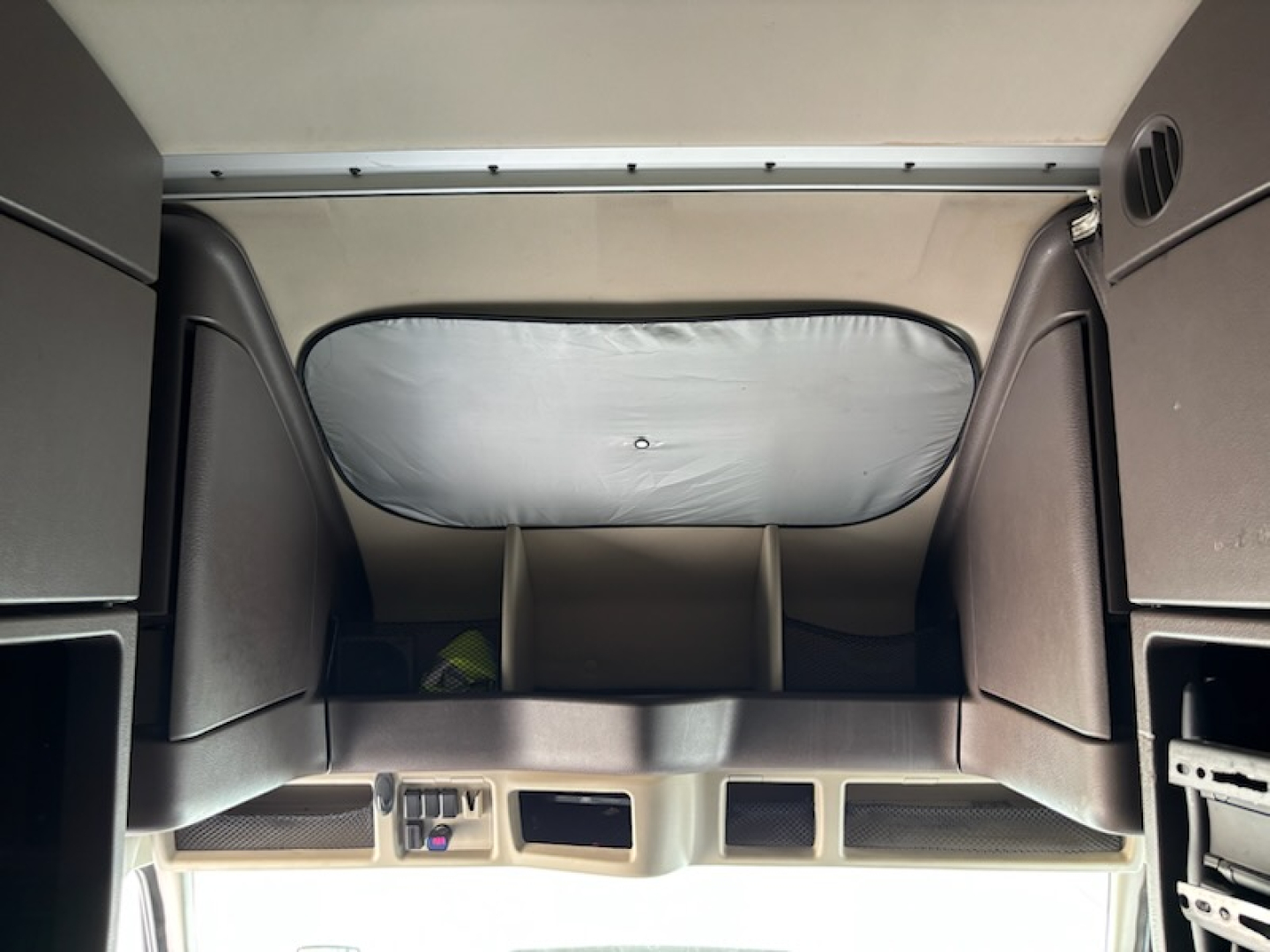 Cab interior of a Volvo VNL780 truck showing sleeper area and overhead storage with partitions.