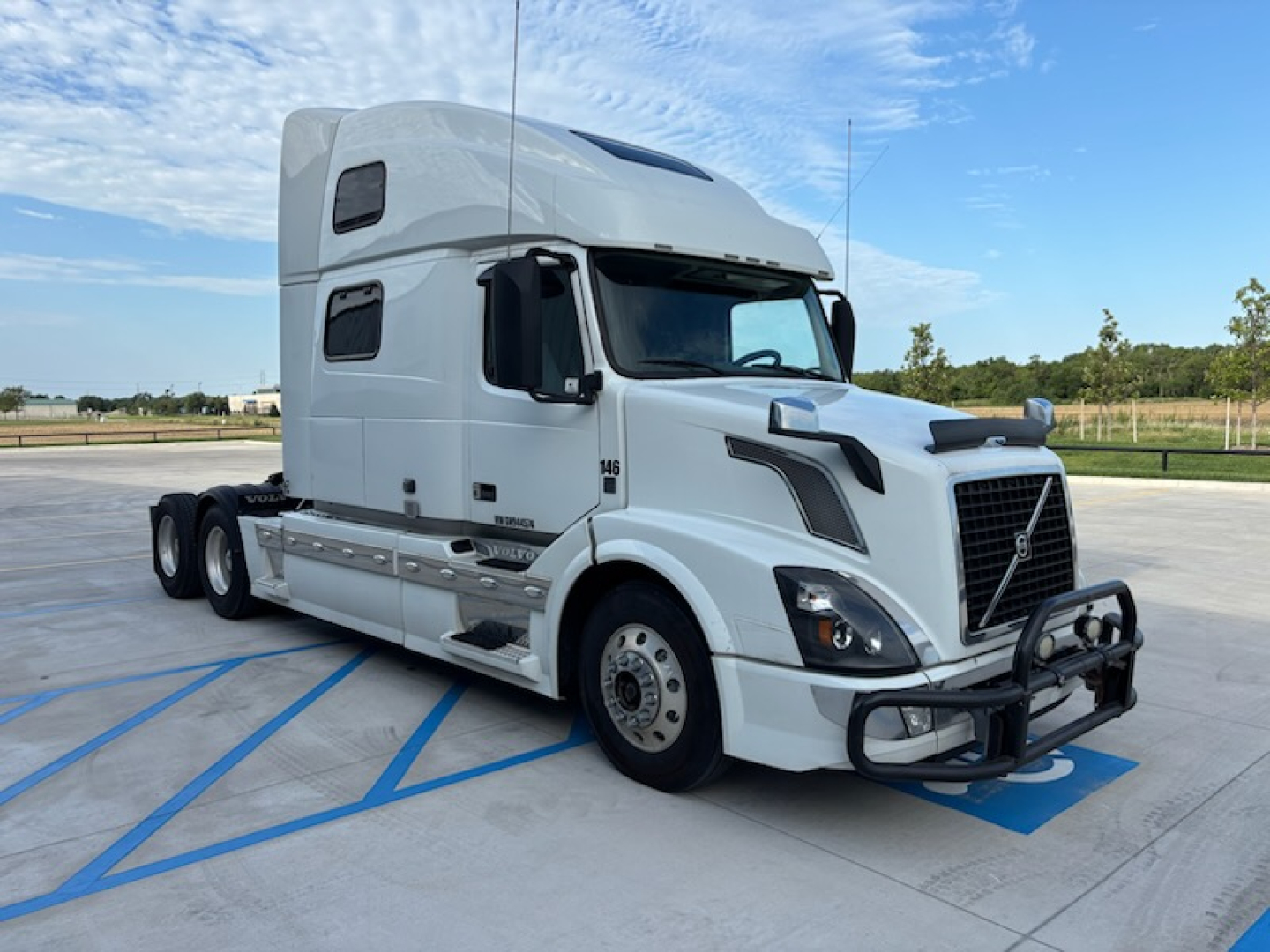Volvo VNL780 highway tractor in white, side view showing sleeper cab, front bumper guard, and dual rear axles.