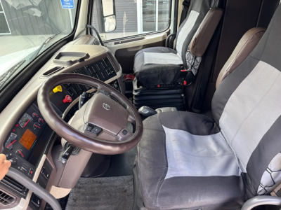 Volvo VNL780 cab interior showing steering wheel, dashboard, driver seat and passenger seat with two-tone fabric covers.