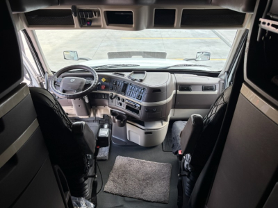Volvo VNL780 truck cockpit interior showing steering wheel, dashboard with control panel and overhead storage, driver and passenger seats, windshield view.