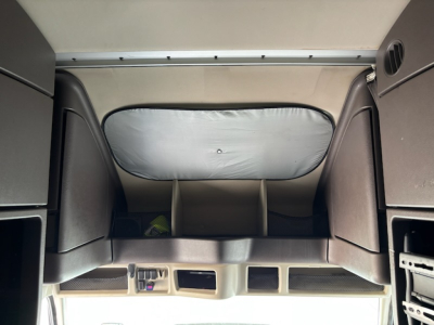 Cab interior of a Volvo VNL780 truck showing sleeper area and overhead storage with partitions.