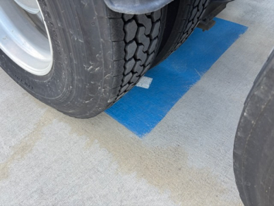 Wheel and tire close-up of a 2016 Volvo VNL780 truck showing a blue parking spot marking on the concrete.