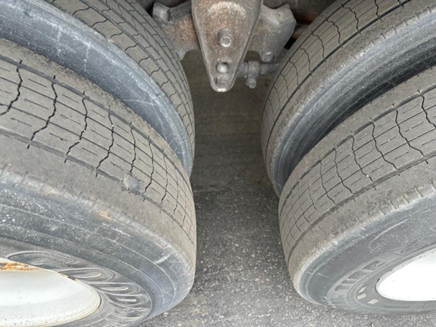 Manac flatbed trailer wheels and undercarriage showing dual rear axle with tires and leaf springs