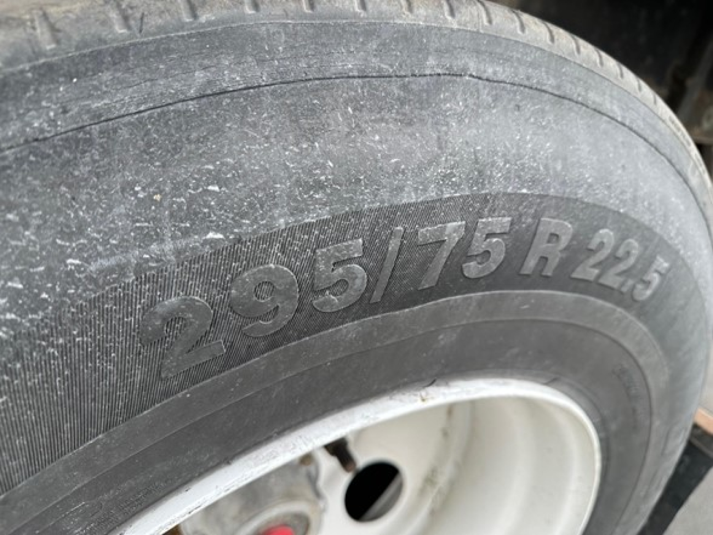 Trailer wheel with tire marking 295/75R25 showing on a flatbed trailer.