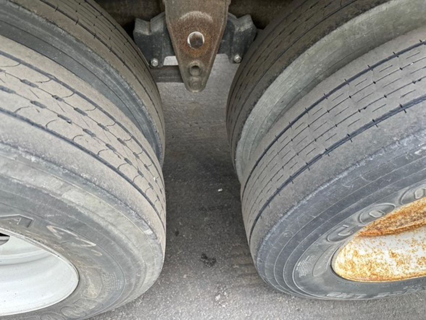 Manac steel flatbed trailer tires and suspension view with dual axles and leaf springs.