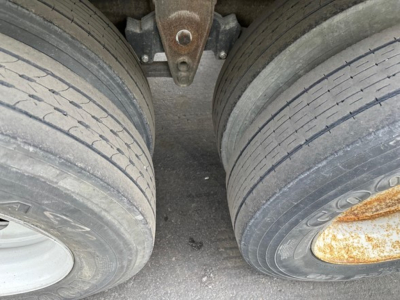 Manac steel flatbed trailer tires and suspension view with dual axles and leaf springs.