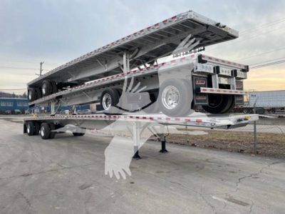 Flatbed trailer with an extended deck raised on a gooseneck, spare tire mounted on side, rear twin axles, reflective safety markings along edges.
