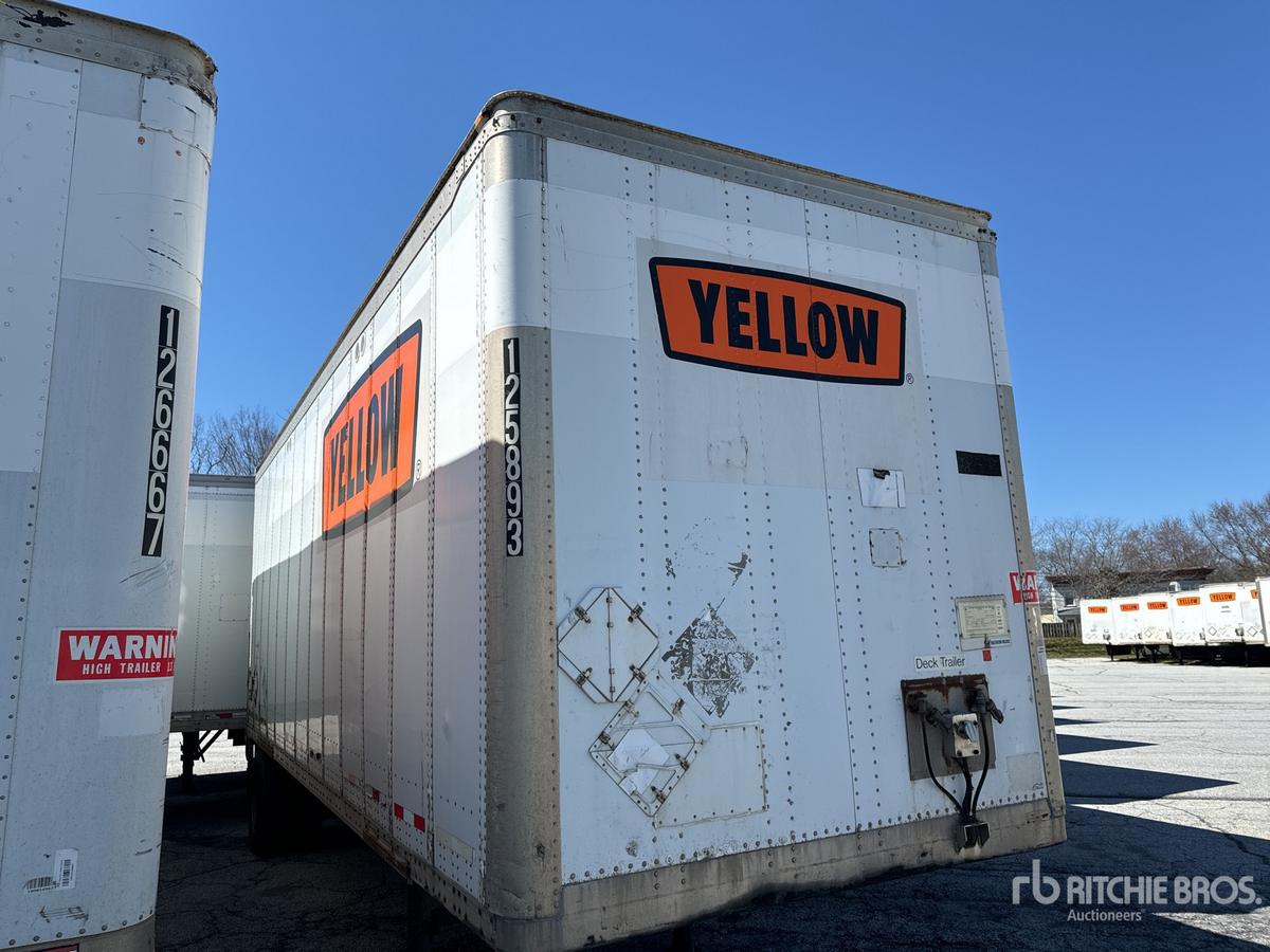 Trailer rear and side view showing large orange 'YELLOW' label on white Wabash equipment trailer with reflective markings and tandem axles.