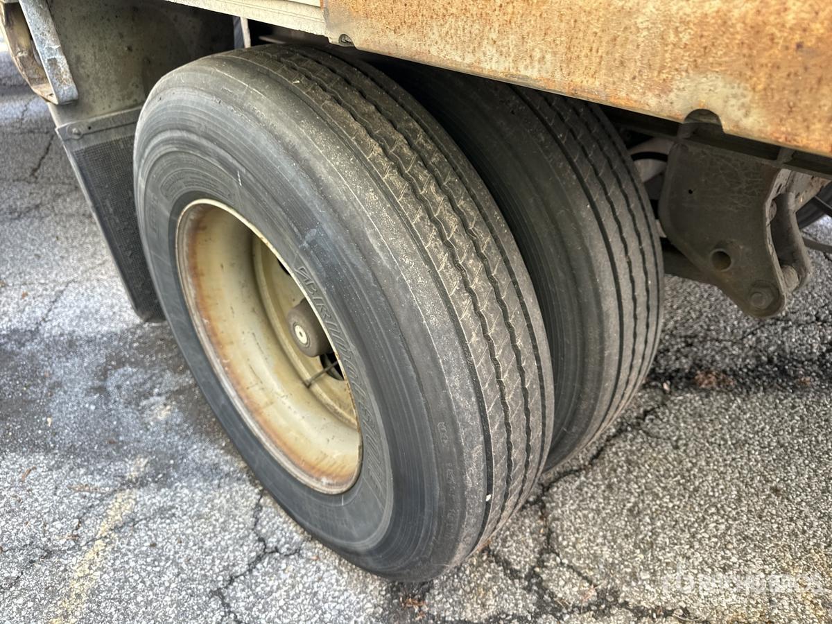Trailer undercarriage with dual rear wheels showing worn tires and rusted frame.