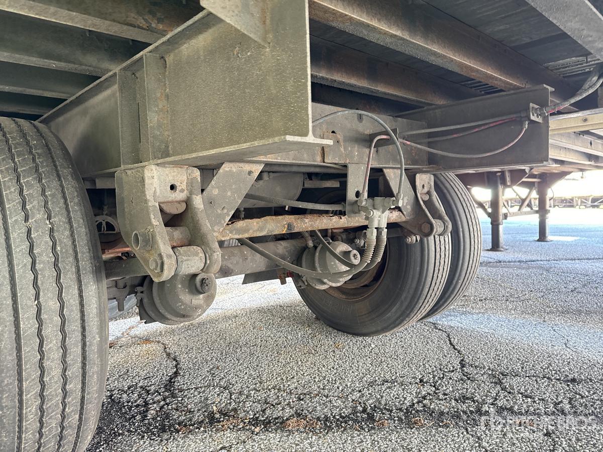 Trailer undercarriage showing axle assembly and suspension components of a Wabash DVD trailer, with dual tires and steel frame, visible undercarriage and leaf springs.