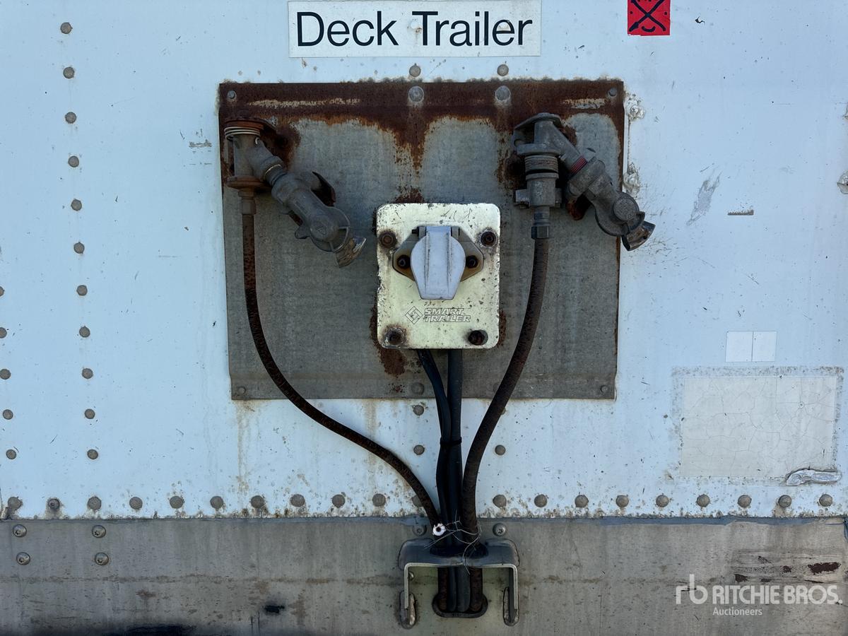 Rear view of a deck trailer showing a central electrical/hosing connection and two side hoses; label 'Deck Trailer' above a rusted connection box; VIN and stock info not visible on this panel.