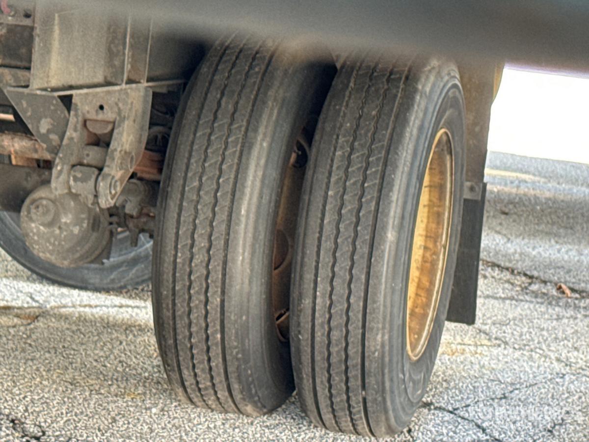 Trailer wheel end with dual rear tires showing rims and suspension components.