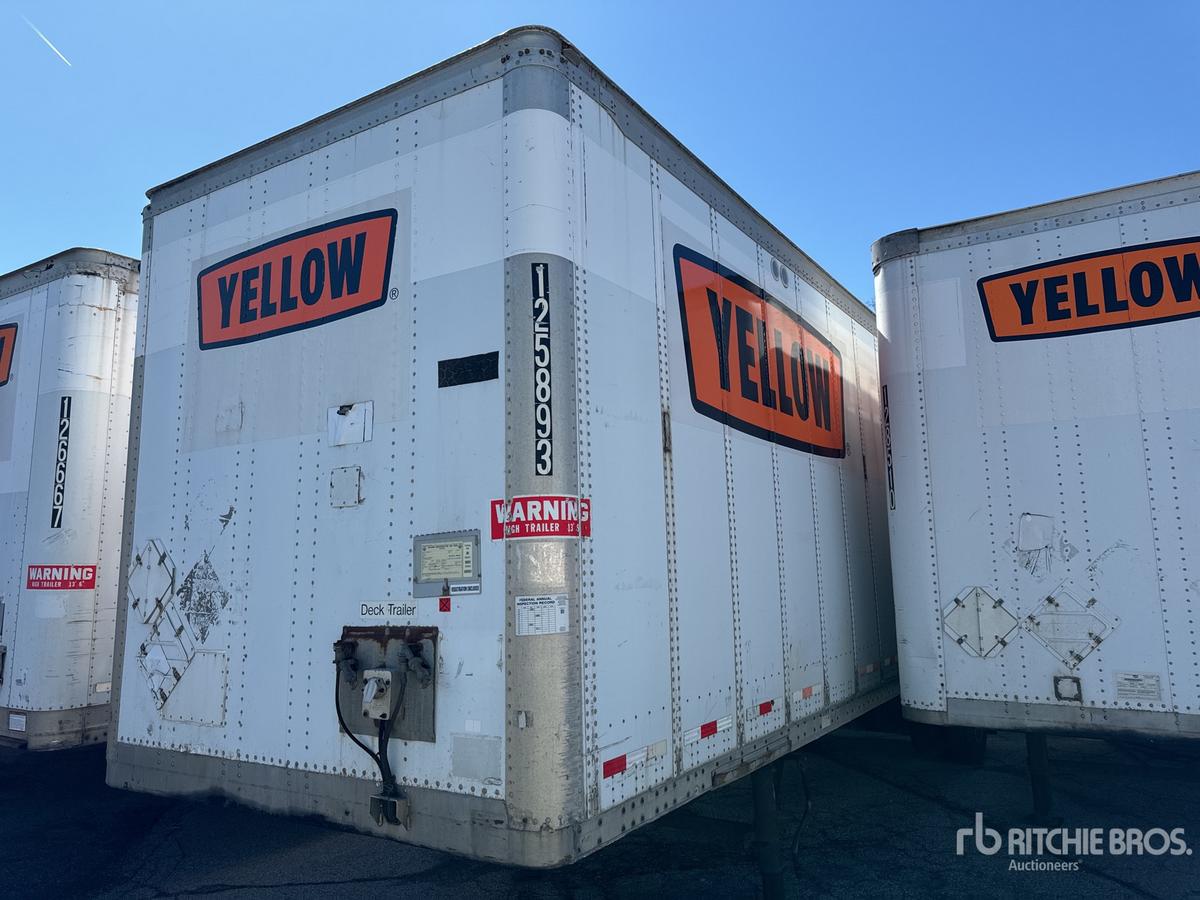 Trailer back view showing YELLOW brand stickers on the sides and rear doors, with a vertical VIN plate and safety warning labels.”,“filename”: