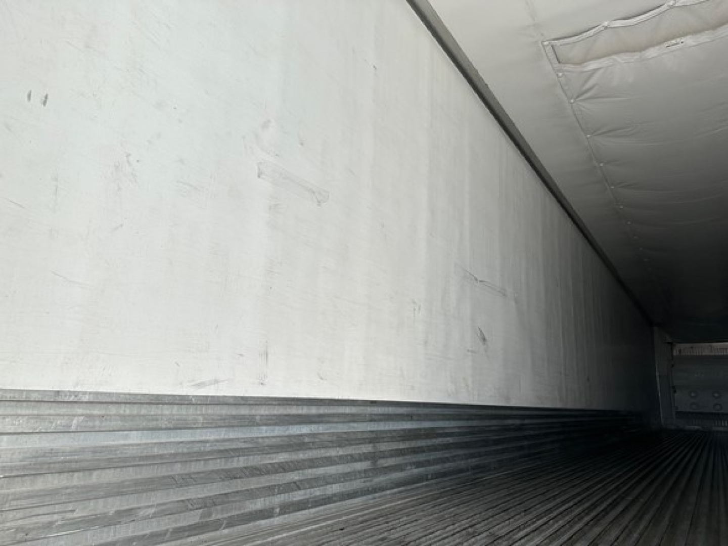 Inside view of trailer cargo area with ribbed metal floor and insulated walls.