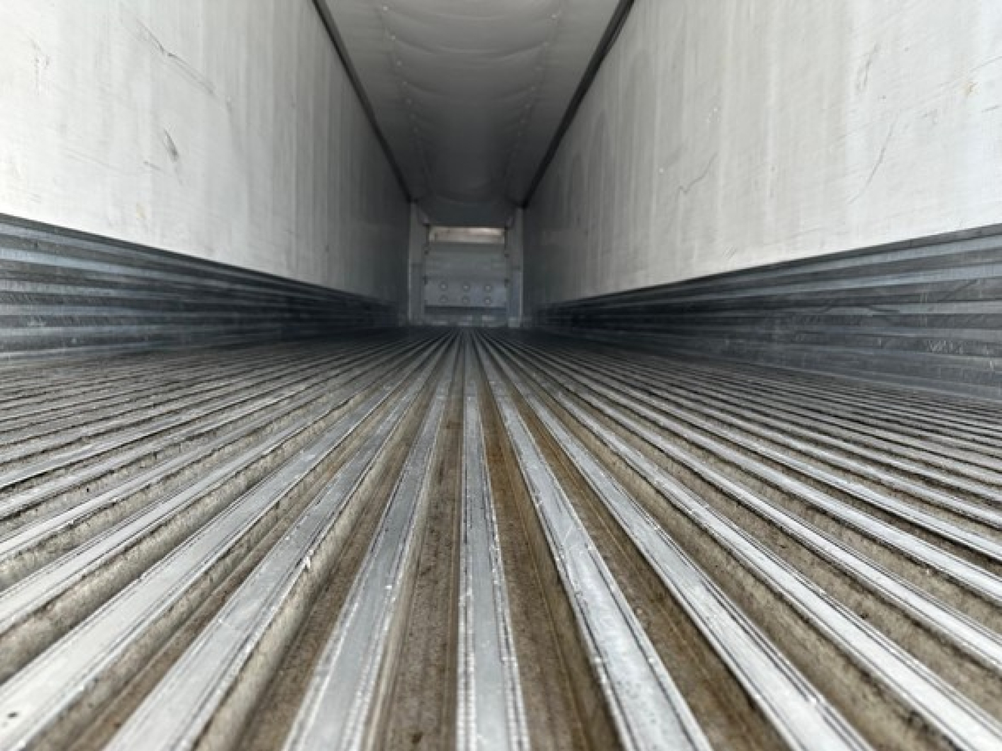 Trailer interior image showing a long empty cargo area with ribbed metal flooring in a Utility 3000R trailer.