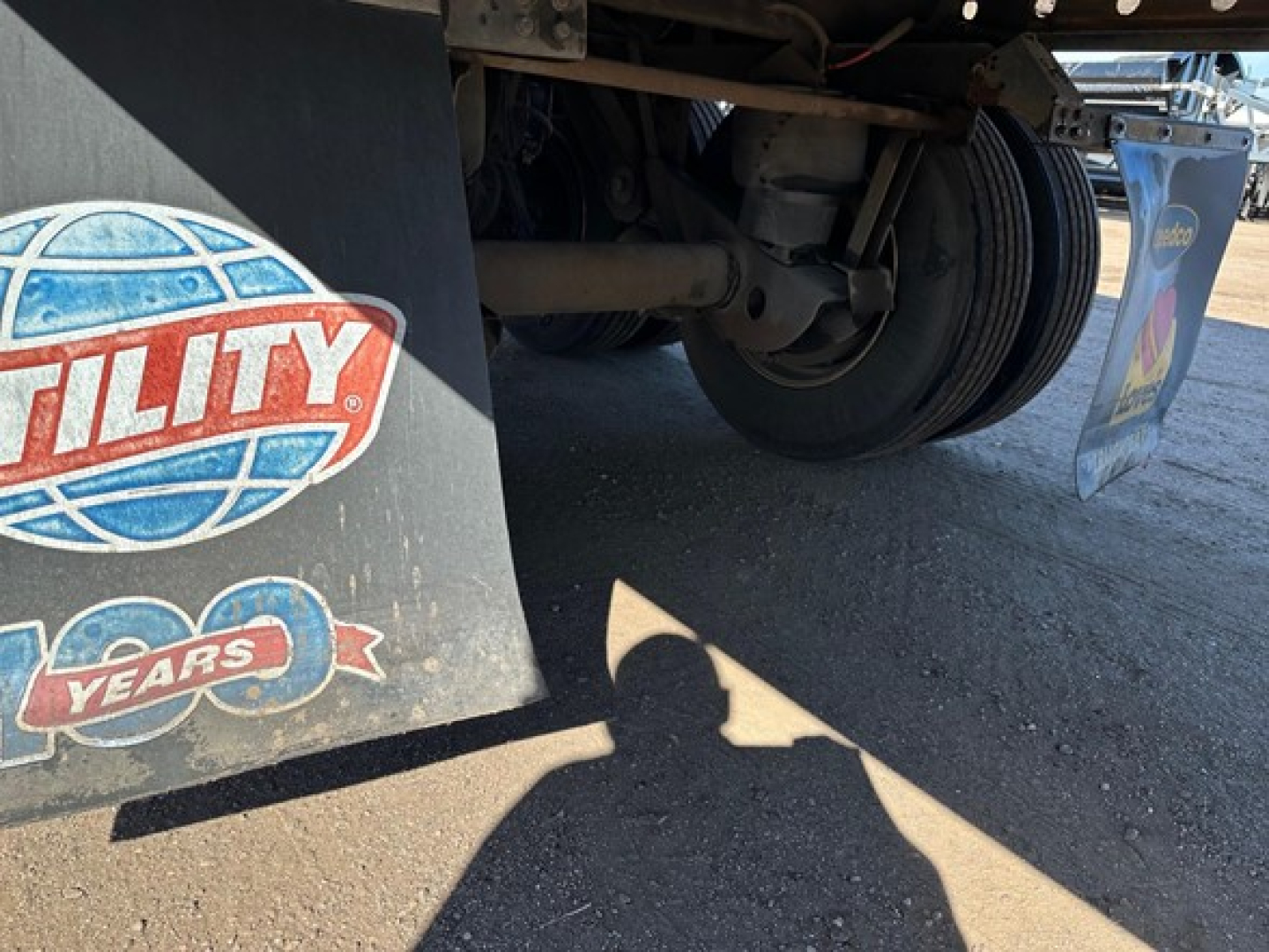 Reefer trailer undercarriage showing wheel assembly and mudflap with Utility logo and 50 years emblem.
