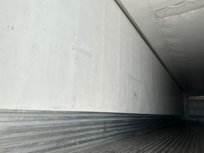 Inside view of trailer cargo area with ribbed metal floor and insulated walls.