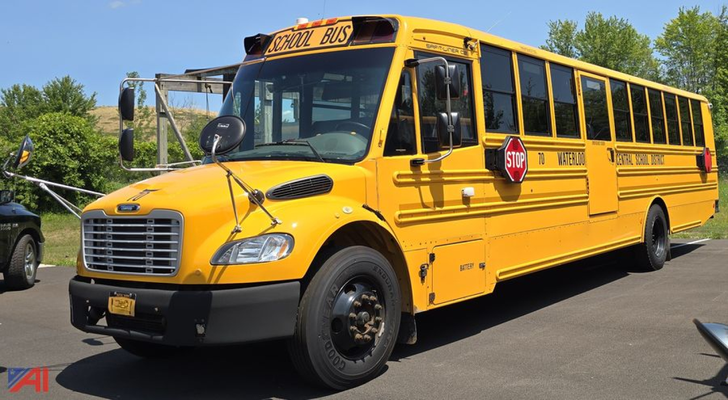 School bus in service yellow Freightliner Thomas B2 C2 with stop sign extended, front grille, black bumper, and side lettering reading School Bus along a row of windows.