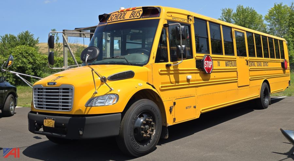 School bus in service yellow Freightliner Thomas B2 C2 with stop sign extended, front grille, black bumper, and side lettering reading School Bus along a row of windows.